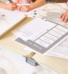 two children sitting at a table with papers on it