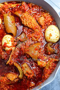 a pan filled with meat and vegetables covered in sauce on top of a blue table