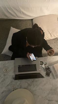 a person sitting at a table with a laptop and cell phone in front of them