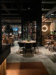 an empty restaurant with tables and chairs in the center, lit up at night time