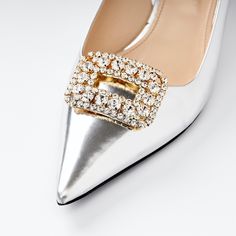 a pair of silver high heel shoes with gold buckles and crystals on the toe