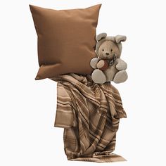 a teddy bear sitting on top of a blanket with a pillow in front of it