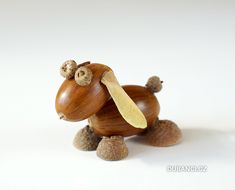 a small wooden toy dog with acorns on it's legs and nose