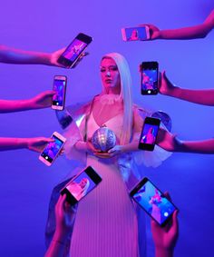 the woman is surrounded by many cell phones in her hands and holding them up with both hands