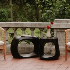 two chairs and a table with flowers on them in front of a stone balcony area