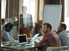 a group of people sitting around a table with laptops and papers in front of them