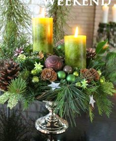 a christmas centerpiece with candles and evergreens on it, surrounded by pine cones