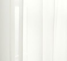 a cat sitting on top of a window sill in front of a white curtain