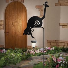 a lamp that is on top of a pole in front of a door and flowers