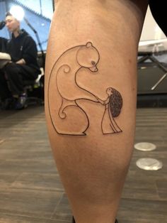 a person with a bear tattoo on their leg, holding the arm of another person