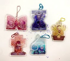 four different shaped key chains on a white surface with glitter and beads around the edges