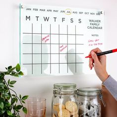 a person writing on a white board next to glass jars with cookies and crackers