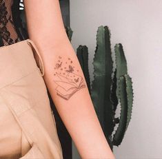 a woman's arm with a tattoo on it and a book in the air