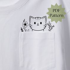 a white t - shirt with a cat in the pocket on it's chest