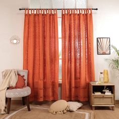 an orange curtain hangs in front of a window with a white rug on the floor