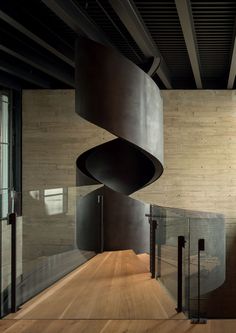 a spiral staircase in the middle of a room with wood flooring and metal railings