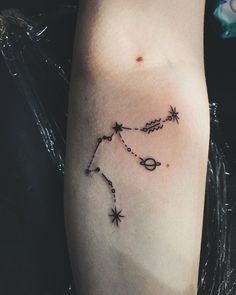 a woman's arm with a tattoo on it that shows the zodiac sign and stars