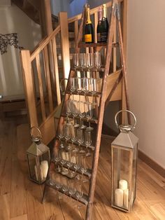 a wooden ladder with wine glasses and candles on the floor next to a stair case