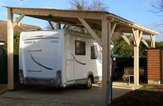 an rv is parked under a wooden structure