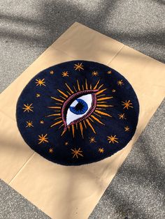 a blue rug with an eye on it sitting on the ground next to a piece of paper