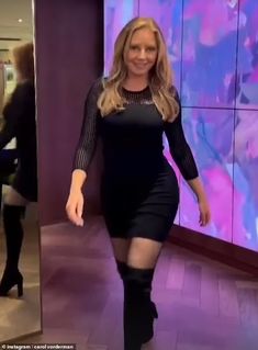 a woman is walking down the street in thigh high boots and a black dress with sheer sleeves