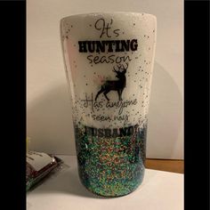 there is a cup that has been decorated with glitters on the bottom and it says hunting season he's anyone seen here