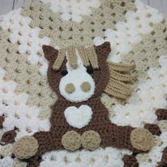 a brown and white crocheted teddy bear laying on top of a blanket with wings