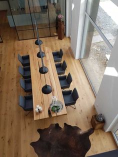 an overhead view of a dining room table with chairs and a cowhide rug on the floor