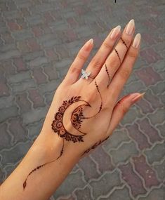 a woman's hand with henna tattoos on it and a diamond in the middle