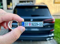 a hand holding a key chain with a car in the background