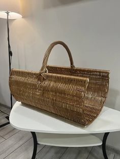 a wicker basket sitting on top of a white table next to a floor lamp