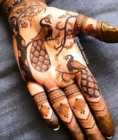 a person's hand painted with henna and peacocks on the palm,