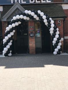 a black and white balloon arch in front of a building with the bell written on it