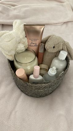 a basket filled with personal care items on top of a white sheet covered bed next to a stuffed animal