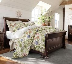 a bed in a bedroom with white walls and wooden furniture, along with a plant