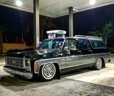 an old station wagon is parked in front of a gas station with its lights on