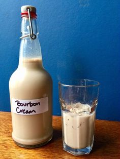 a bottle of bourbon cream next to a glass with ice and cinnamon on the table