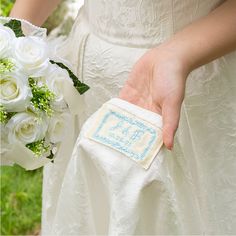 a person in a wedding dress holding a white bouquet with blue writing on the side