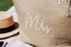 a close up of a pillow with the word mrs on it next to a hat