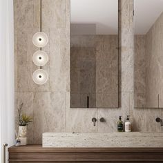 a bathroom with two sinks and three lights hanging from the wall above it, along with a large mirror on the wall