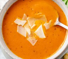 a white bowl filled with soup next to some crackers and lettuce leaves