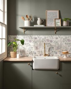 a kitchen with green cabinets and white tile backsplash, gold faucets