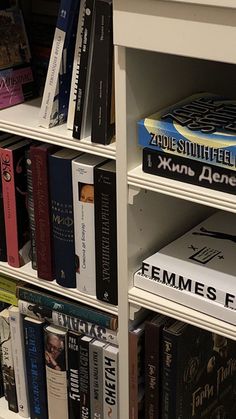 a book shelf filled with lots of books on top of white shelving unit shelves