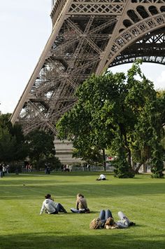 people sitting on the grass in front of the eiffel tower