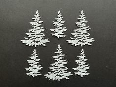 small white christmas trees on a black surface with space for the wording ornament