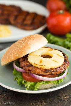 a burger with pineapple slices and onions on the bun is sitting on a plate