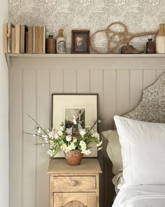 a bed room with a neatly made bed and a shelf filled with books on top of it