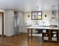 a kitchen with an island, refrigerator and sink in it's center area is shown