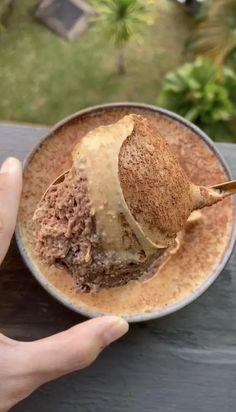 a person holding a spoon full of ice cream and some kind of cake on a plate