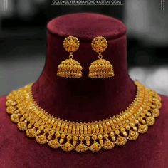 a gold necklace and earring set on display in a shop window, with the caption's name below it